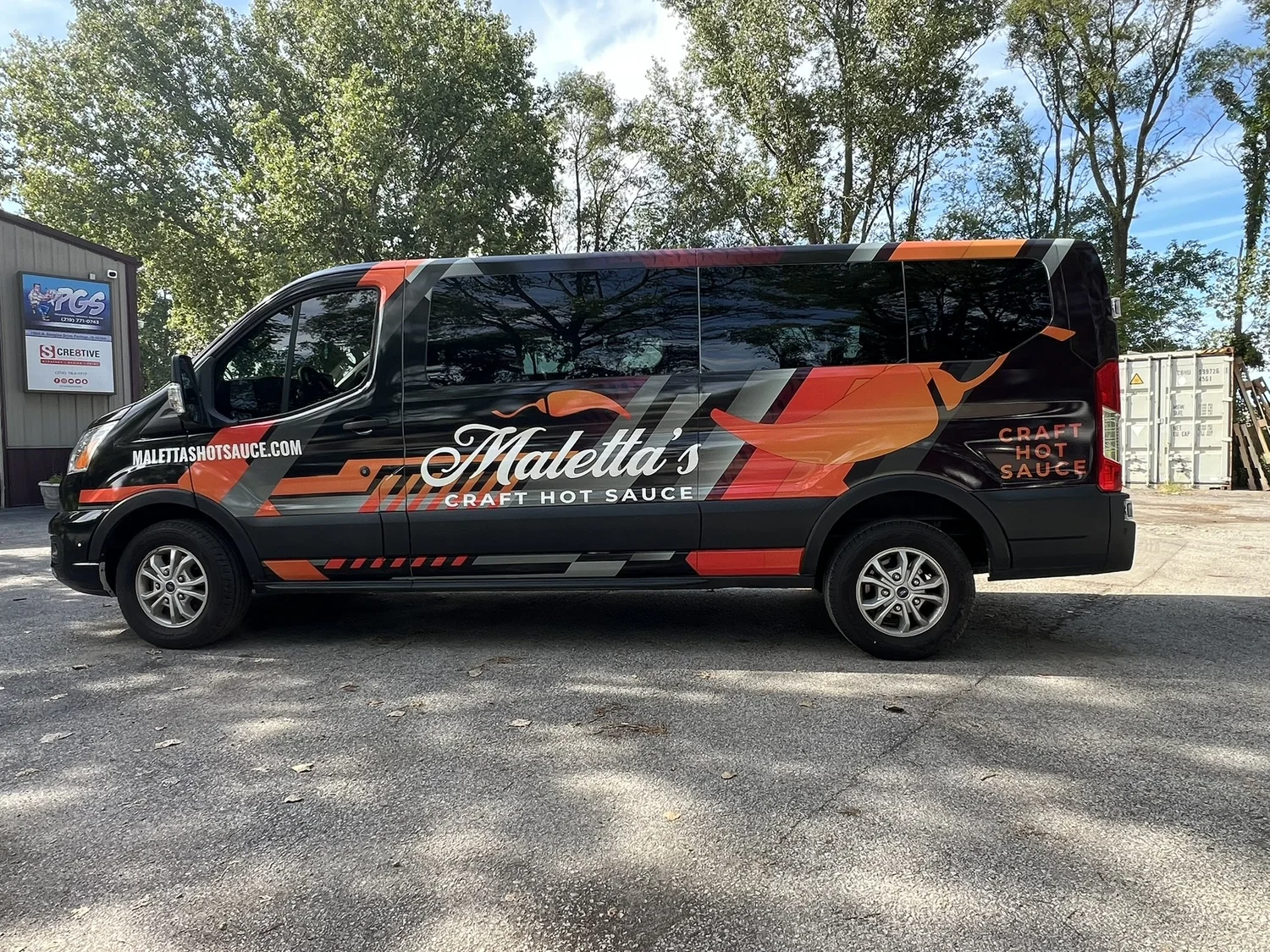 A black commercial service van with red and white company wrap graphics