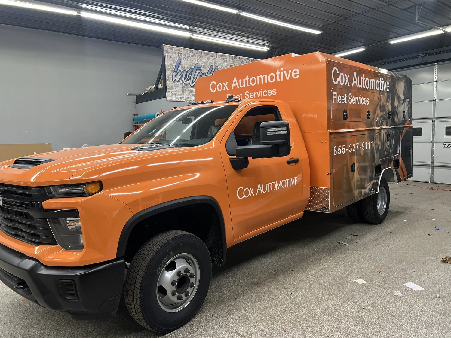 An orange Cox Automotive commercial service truck with branded wrap graphics